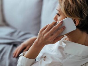 Pensive woman talking on the phone while relaxing on the sofa at