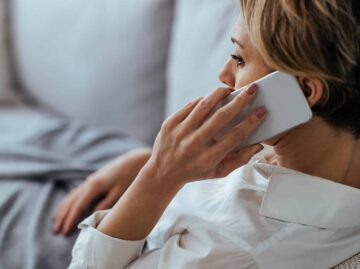 Pensive woman talking on the phone while relaxing on the sofa at