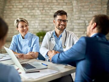 Happy doctor shaking hands with a businessman on a meeting in th